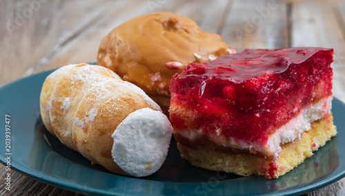 Foto Cream puff, cream roll and raspberry jelly cake on plate
