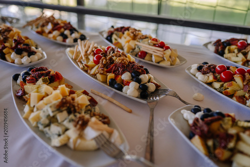 Canvas-taulu Assorted cheese platter with fruits, nuts, and crackers arranged on white servin