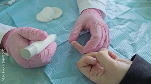 Blood test process in a medical setting with healthcare staff in gloves performing a finger prick