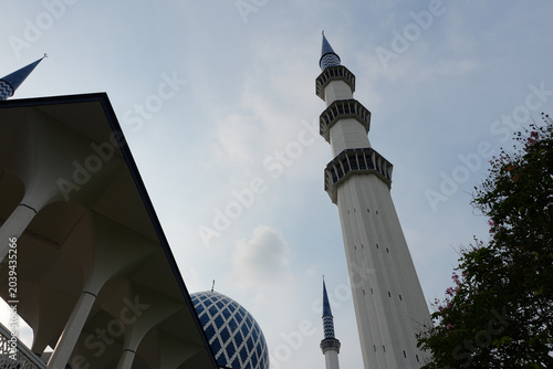 Foto The grand minaret of the Sultan Salahuddin Abdul Aziz Mosque under a cloudy blue sky