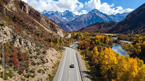 A car drives along a scenic road through a mountain valley
