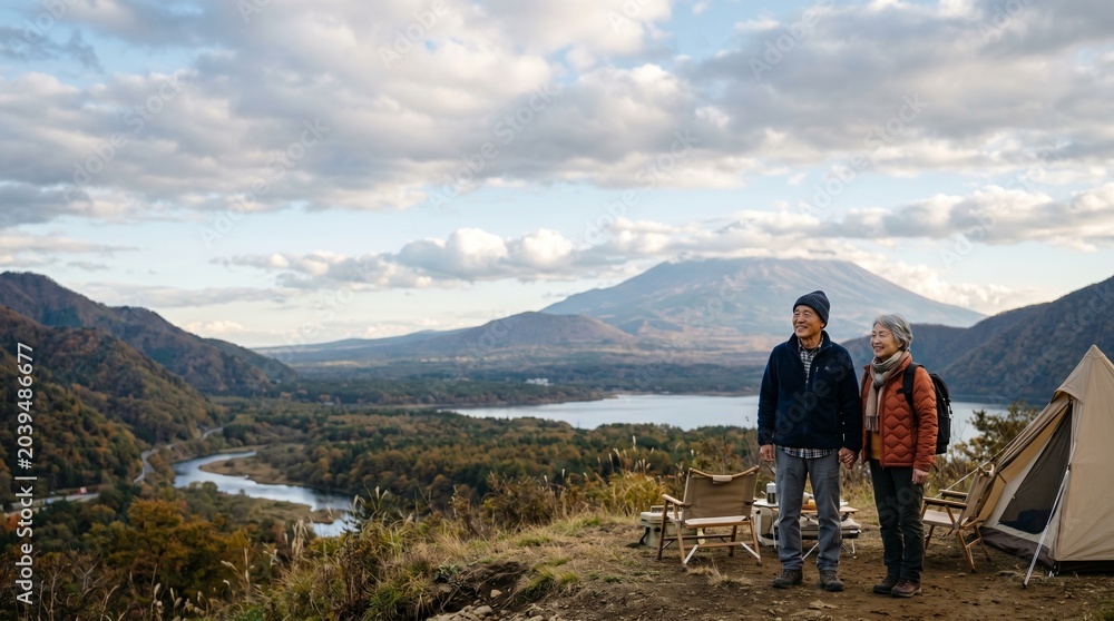 Fototapeta premium 広大な自然風景の中に佇む日本人シニア夫婦。 空と大地が広がる開放感あるアウトドアシーン。