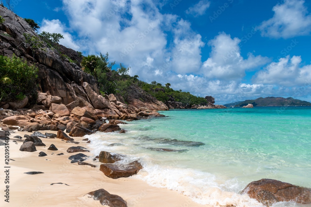 Obraz premium Rocky tropical beach with turquoise water and dramatic clouds - Seychelles