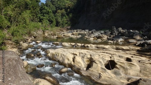 Foto Dynamic river stream cascading over unique ancient rock formations in a vibrant,