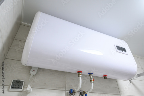 Fotografie white horizontal electric water heater mounted on a light-colored tiled wall, fe
