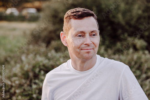 Man with subtle smile looking away in summer countryside portrait