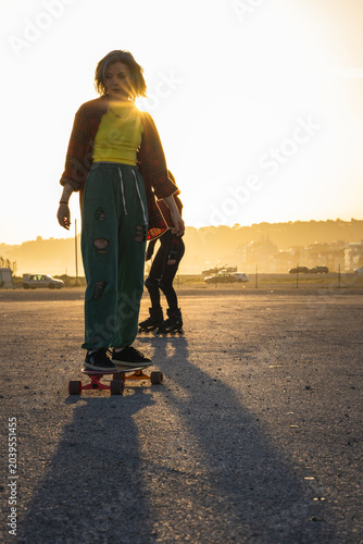 Tableau sur toile Young woman skateboarding enjoying golden hour backlighting