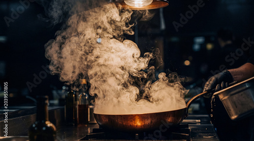 Foto Dramatic close-up photograph of a professional chef cooking with a pan on a hot stove