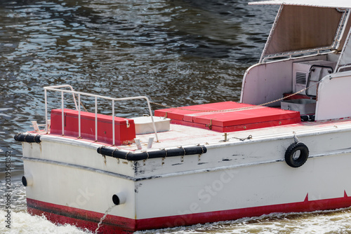 Фотография White and red utility boat with black rub rails moving through rippling water, f