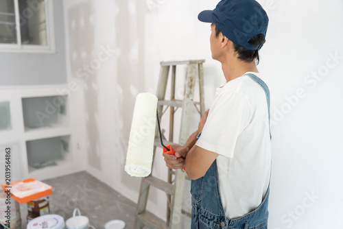 Photos painter man, brush in hand for products to restore and paint the wall, indoor th
