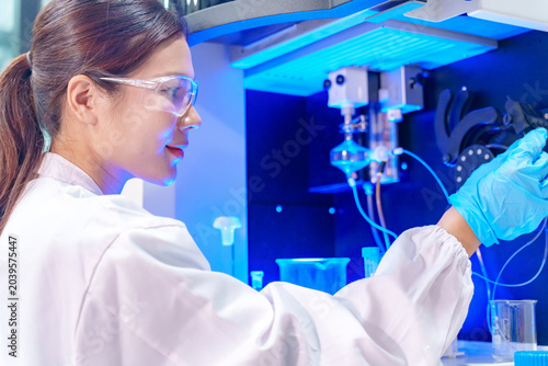 Scientist in lab coat and safety glasses works with advanced analytical equipment