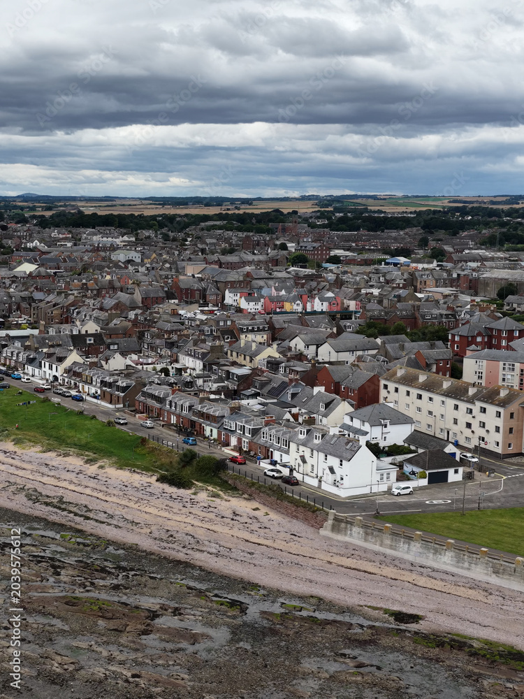 Obraz premium Aerial View of Dundee Coastal Town with Rocky Shoreline and Cloudy Sky