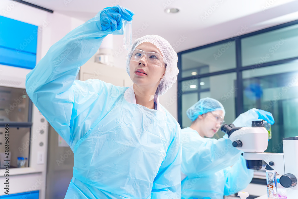 Fototapeta premium Scientists in protective gear conduct research with test tubes and microscopes in a lab