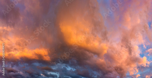 Heavenly landscape. The colorful sunset sunlight painted the cumulus clouds beautifully. Panorama.