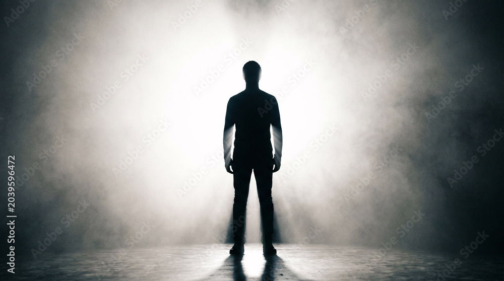 Fototapeta premium A mysterious man stands perfectly still in a powerful silhouette featuring sharp edges and dark tones captured with high contrast lighting in a cinematic style.