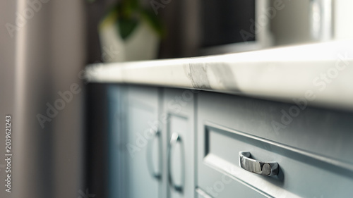 Close up of modern blue kitchen cabinets with marble countertop and shallow depth of field in minimalist home interior.