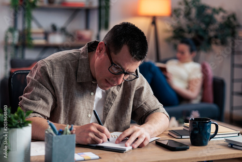 Canvas Print Man writing notes at home office desk concentrating on work