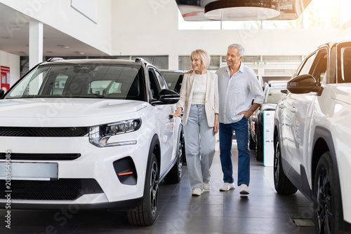 фотографія Senior couple walking through modern car dealership showroom while exploring new