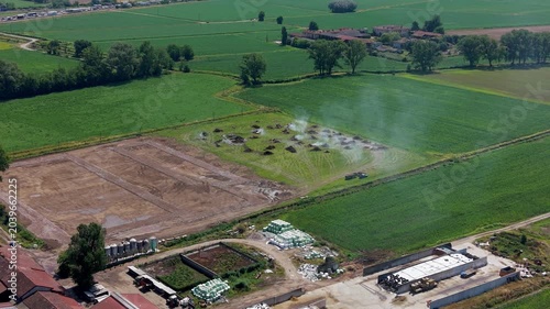 Top-down drone shot of multiple small fires in a dry grass field, showing controlled burning process in a rural area.