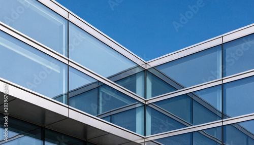 Modern glass building facade with geometric architectural details and blue sky