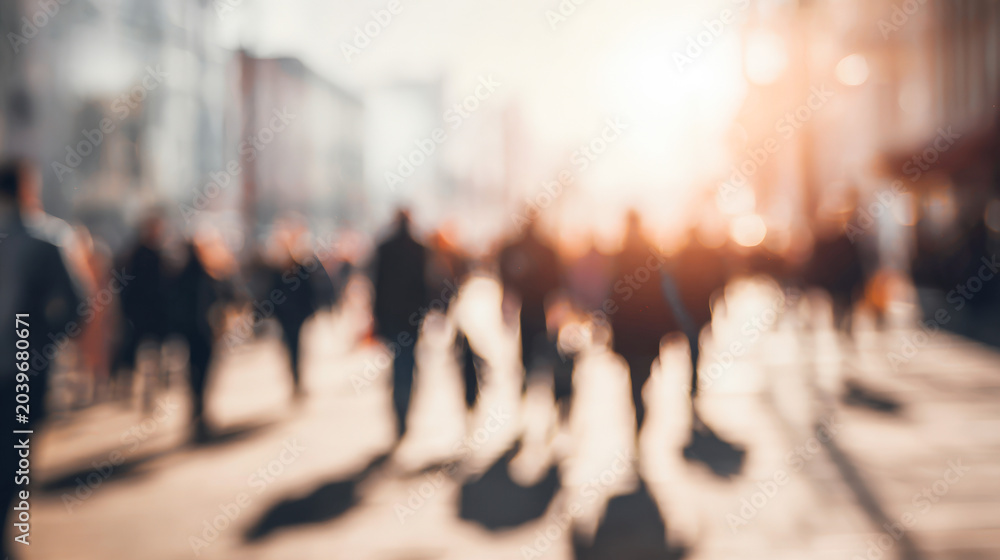 Obraz premium Walking in the city as a group of people create movement in an urban scene with sunlight shining