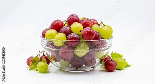 Fresh mixed green and red grapes in clear glass bowl on white background minimalist still life