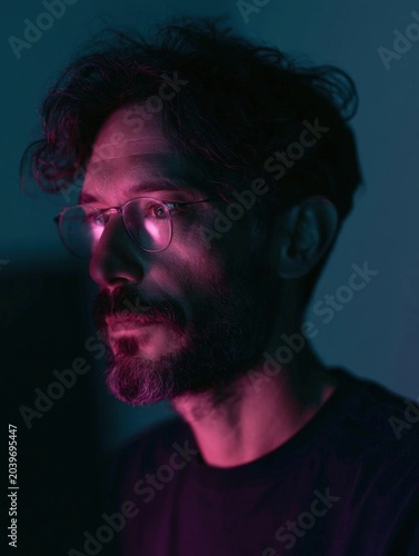 Portrait of a man with a beard and glasses. he is facing away from the camera, with a serious expression on his face.