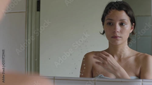 Young Woman Looking At Her Reflection In A Bathroom Mirror During Her Morning Self-Care Routine
