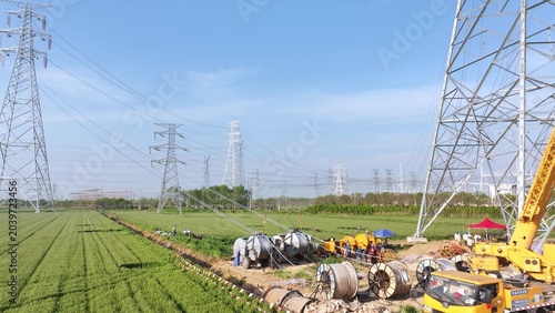 Tableau sur toile Construction scene with power line towers and workers under high voltage transmi