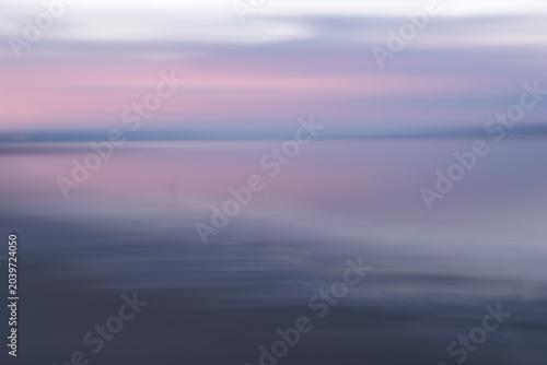 Soft pink and purple sky meets calm, misty water