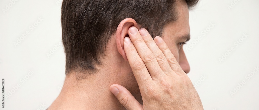 Fototapeta premium Man touching his ear with his hand on a white background with a concerned expression
