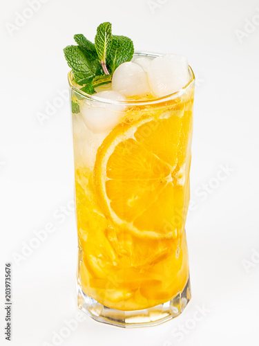 Refreshing orange and mint lemonade cocktail in a glass with ice, isolated on a white background.