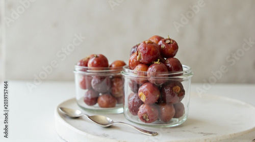 Delicious jujubes in glass jars on white marble plate