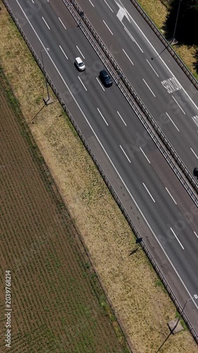 Aerial View of Highway A50: An aerial perspective reveals a two-lane highway stretching across a landscape of agricultural fields and grassy verges, Italy, Milan