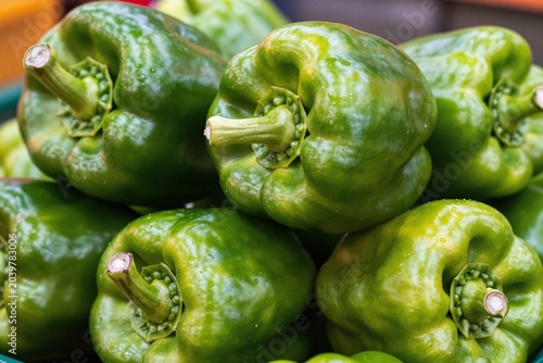 A pile of green bell peppers sitting on top of each other
