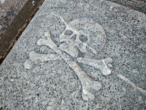Cuadro en lienzo Skull and crossbones carved into medieval tombstone as memento mori symbol