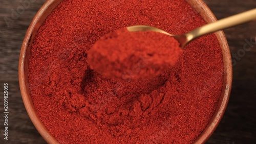 Smoked paprika scooping with spoon from bowl, close up