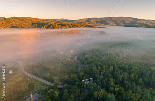 Quadro su tela Sunrise mist settling over a tranquil rural valley, revealing a winding river an