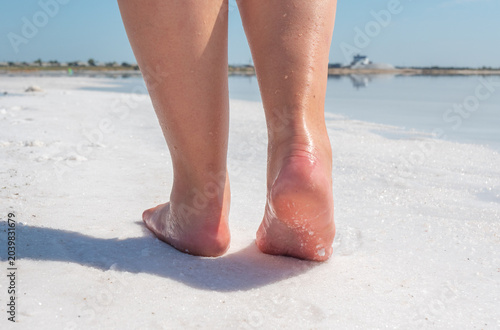 Barefoot steps on the bright white salt crust of Bursol lake under a clear blue sky
