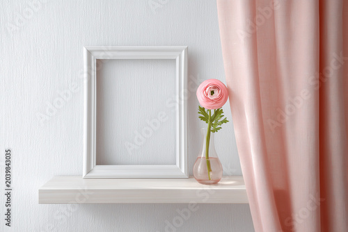 A simple white frame on a shelf with a pink flower in a vase and a pink curtain