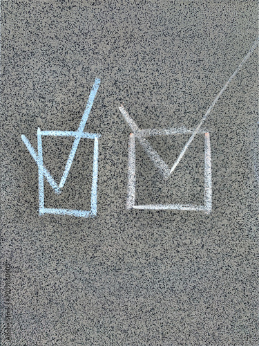 Two hand-drawn chalk checkmark symbols in boxes on grey granite tile, concept of success, checklist and task completion