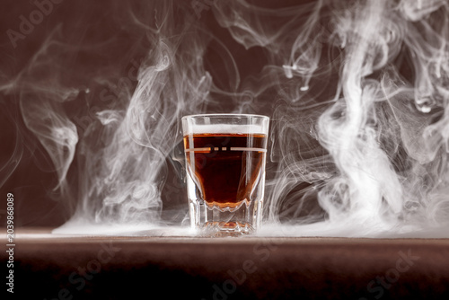 Konstfotografi Whiskey in a traditional shot glass surrounded by a smokey bar top