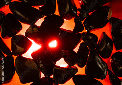 Incandescent stone texture, a dark stone texture with an ember effect underneath and a dark background, selective focus.