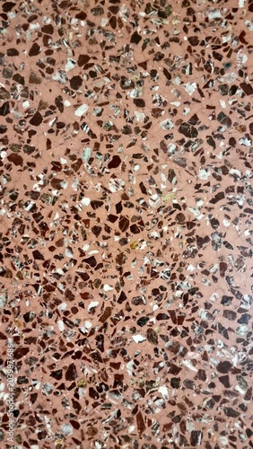Close-up view of a pink terrazzo floor featuring scattered marble stone chips in brown, white, and gray tones