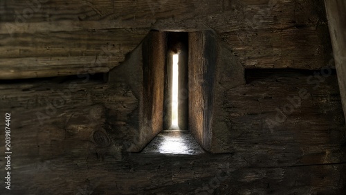 blockhouse. Close-up of a narrow arrow slit in a wooden wall, a single beam of light shining through, detailed wood. real-estate listings.