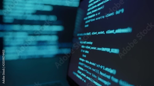 Close up of laptop screen with programming code in dark environment, blue glowing code lines on display and background. Data science software development and coding concept. 