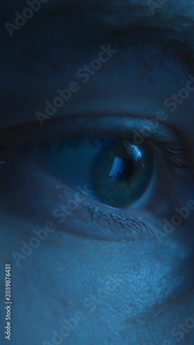 Close-up of man eyes looking with focus on a computer or smartphone display with the screen reflection in his pupil, working late at night or scrolling through a news feed. Vertical video