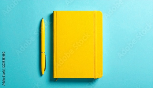 Yellow notebook and pen on blue background, vibrant modern contrast.