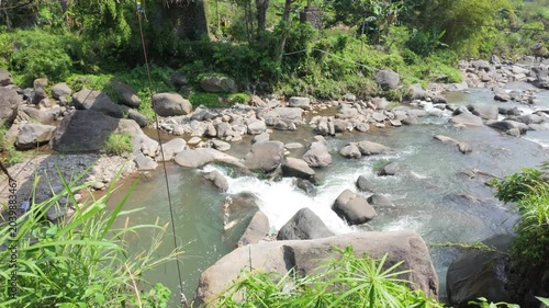 A tranquil stream flowing over smooth stones surrounded by lush greenery creating a peaceful natural scene