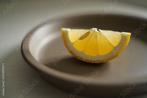 Single lemon slice on brown plate refreshing citrus wedge for beverage garnish